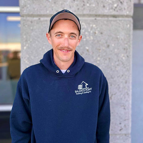 Corey wearing a navy Balance Point sweatshirt and a baseball cap smiling at the camera