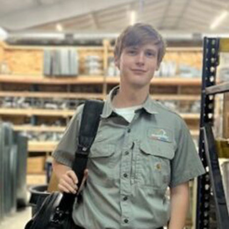John Dodson standing in the shop with a tool bag over his shoulder