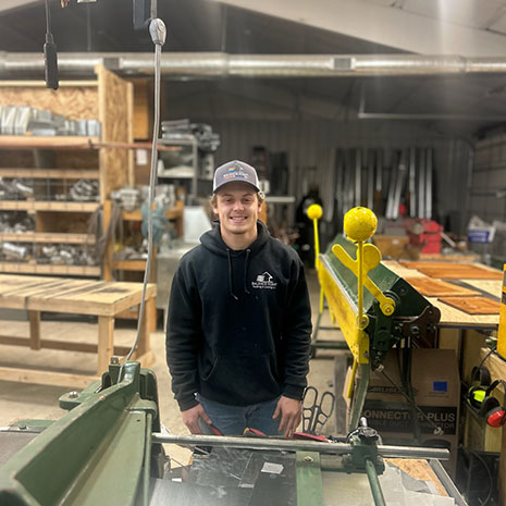 Jack Baird wearing a sweatshirt and hat standing in a mechanical shop