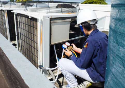 man checking pressure on commercial A/C unit